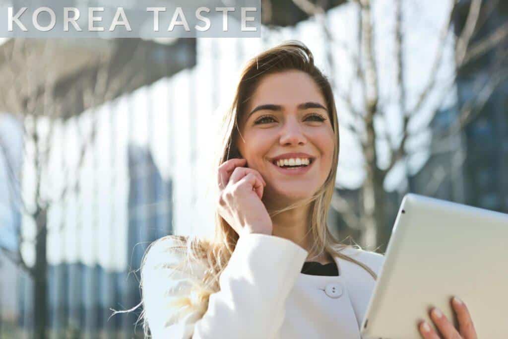 Confident businesswoman using her tablet and phone, smiling outdoors in sunlight.